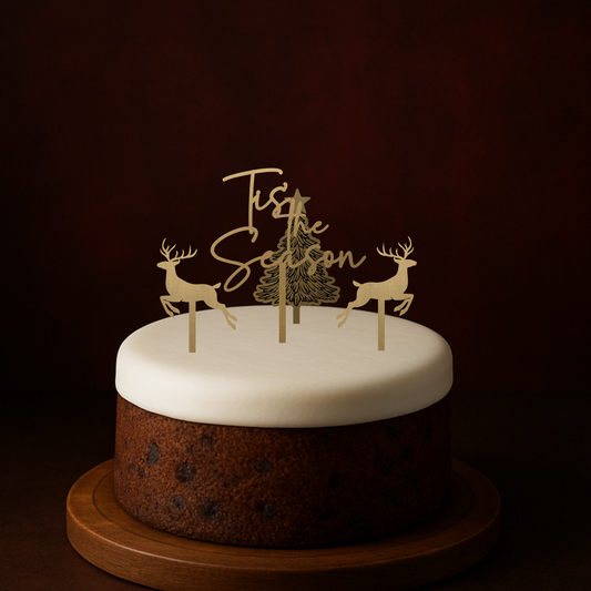 Small cake with reindeer and tree topper on a dark background